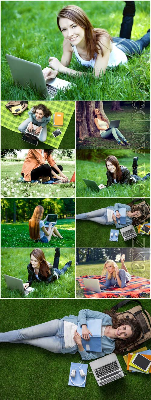 Girls with laptop lie on green grass stock photo